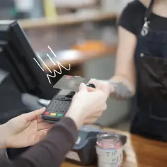 Zbliżenie na płatność kartą debetową przy terminalu płatniczym.